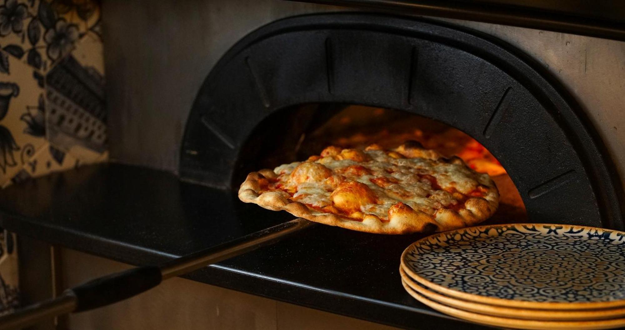 Eme カテドラル ホテル セビリア エクステリア 写真 Pizza being removed from a wood-fired oven